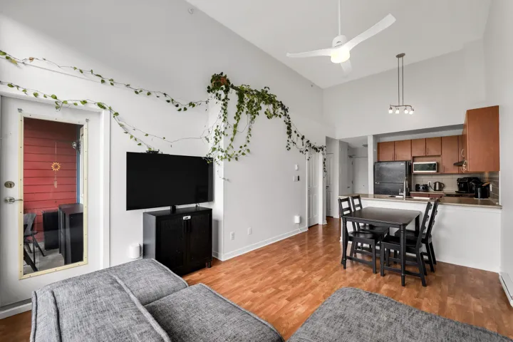 Living room featuring a high ceiling, light wood-type flooring, and ceiling fan