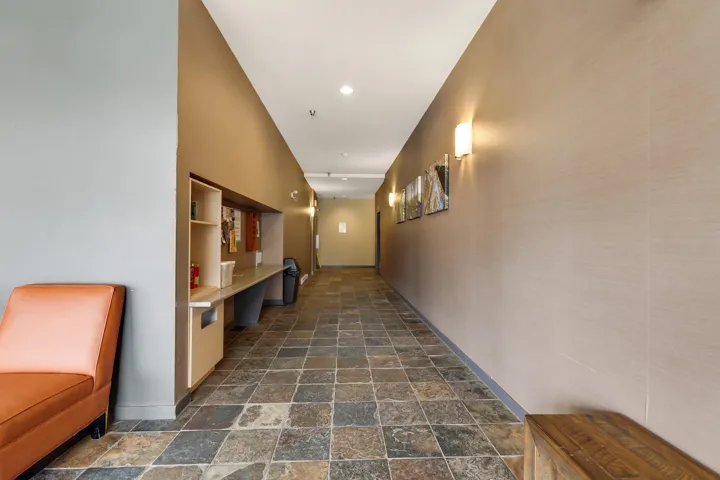 Corridor featuring dark stone finish flooring, an office area, and recessed lighting