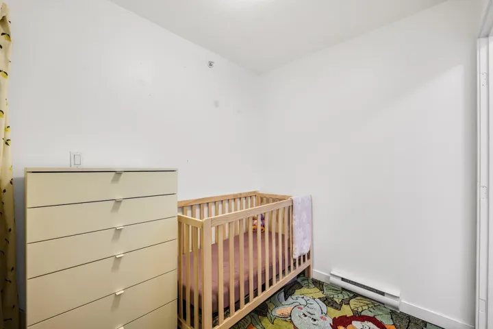 Bedroom featuring a nursery area and a baseboard heating unit