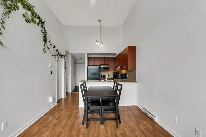 Dining space with a high ceiling, baseboard heating, and light wood-type flooring