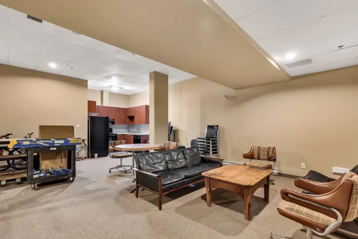 Living room with light colored carpet, a high drop ceiling, and recessed lighting