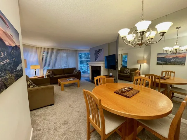 Carpeted dining room featuring a notable chandelier, a fireplace, and a textured ceiling