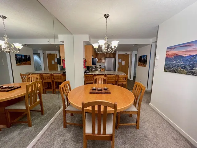 Dining space featuring baseboards, a textured ceiling, a chandelier, and carpet flooring