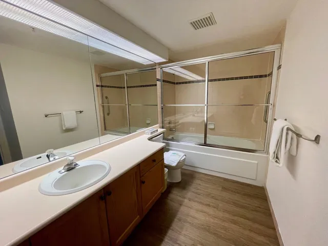 Full bath with visible vents, toilet, wood finished floors, combined bath / shower with glass door, and vanity