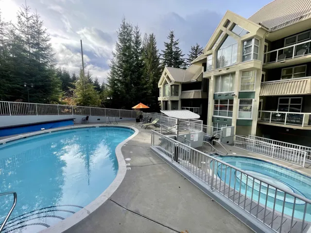 Community pool with a patio, fence, and a hot tub