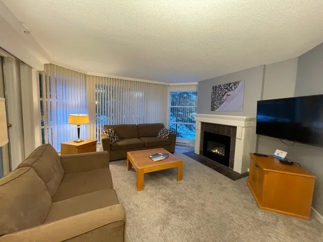Living room featuring a textured ceiling, carpet flooring, and a tile fireplace
