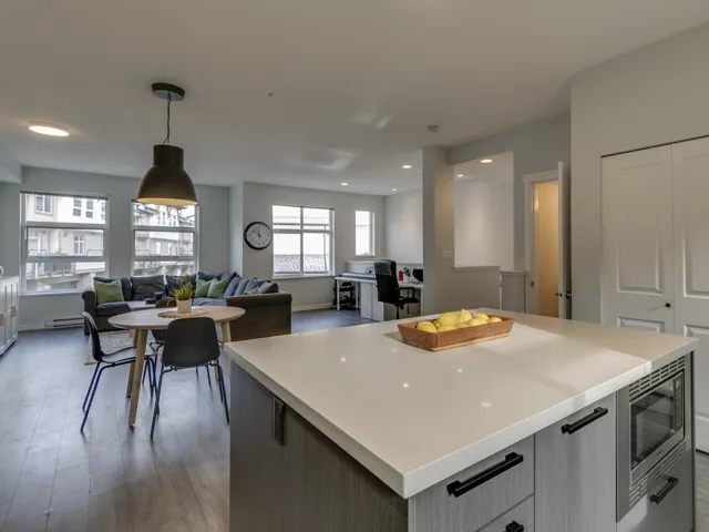 Kitchen featuring stainless steel microwave, pendant lighting, light countertops, open floor plan, and gray cabinetry