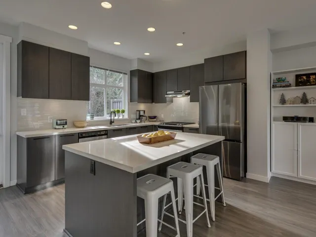 Kitchen featuring appliances with stainless steel finishes, a kitchen bar, light wood-style flooring, decorative backsplash, and modern cabinets