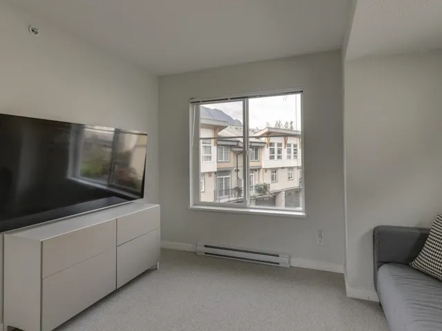 Living area featuring light colored carpet and a baseboard heating unit