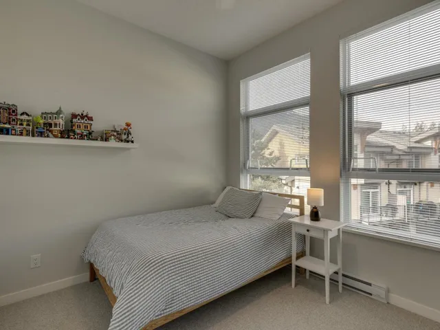 Bedroom with light carpet and baseboard heating