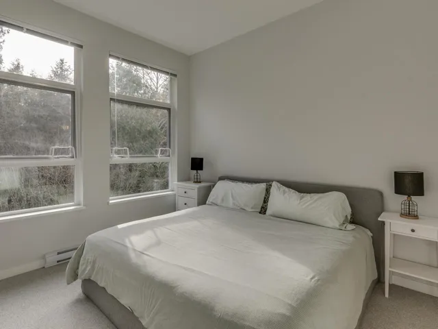 Bedroom with light colored carpet and baseboard heating