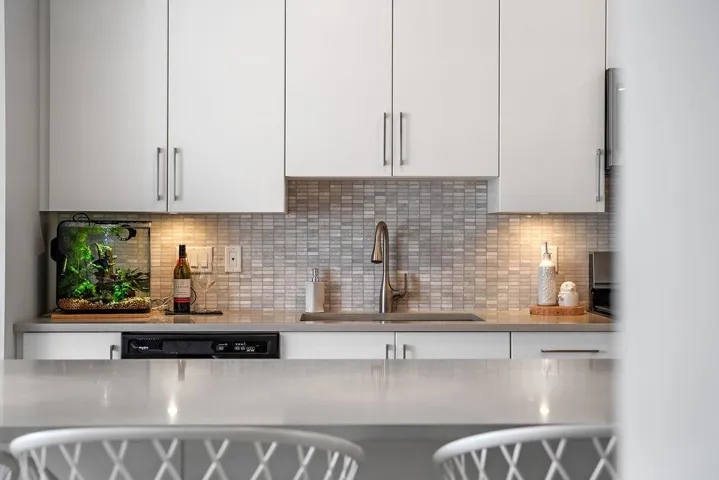 Kitchen featuring white cabinetry, dishwashing machine, tasteful backsplash, light countertops, and modern cabinets