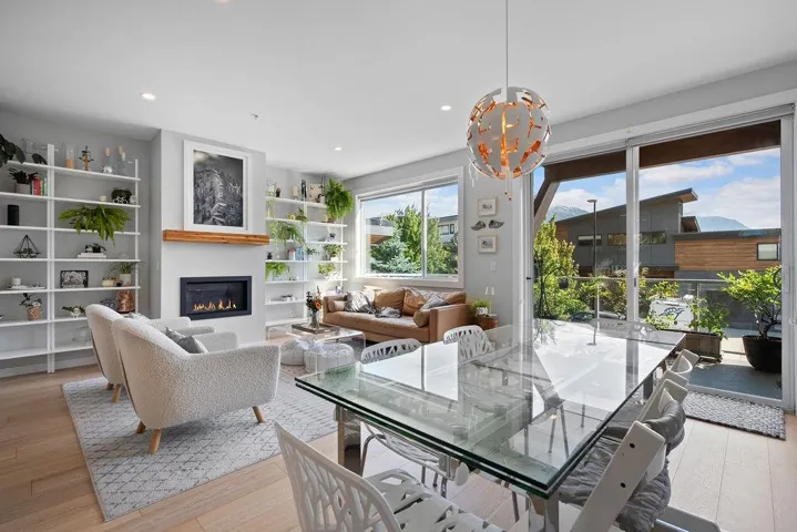 Living room featuring a glass covered fireplace, wood finished floors, a chandelier, and recessed lighting