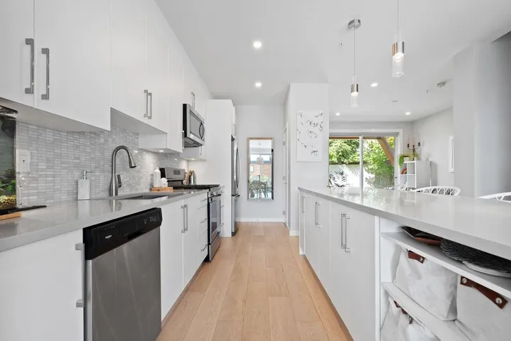 Kitchen with stainless steel appliances, white cabinetry, light wood finished floors, tasteful backsplash, and recessed lighting