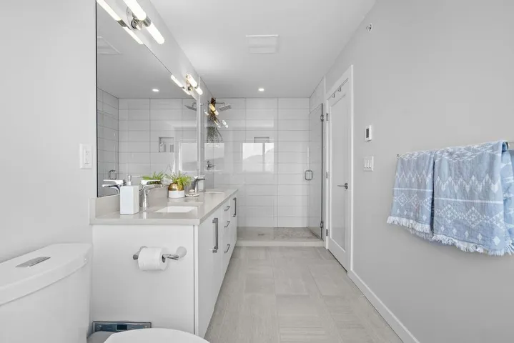 Full bath featuring double vanity, a shower stall, and recessed lighting
