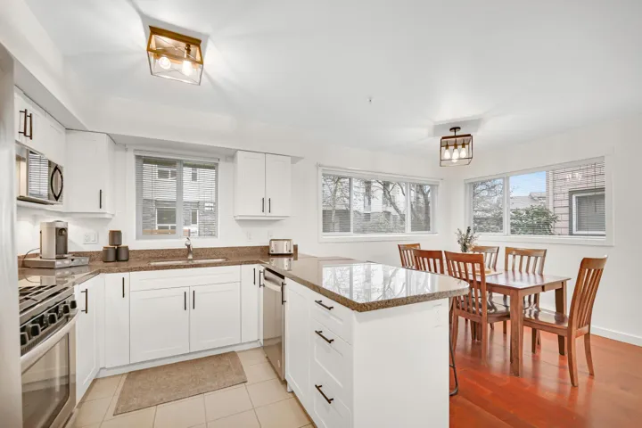 Kitchen featuring stone countertops, a peninsula, white cabinetry, appliances with stainless steel finishes, and a sink