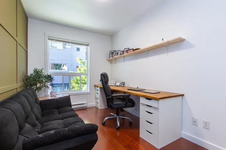 Bedroom converted to office area with built in desk, a baseboard heating unit, baseboards, and dark wood finished floors