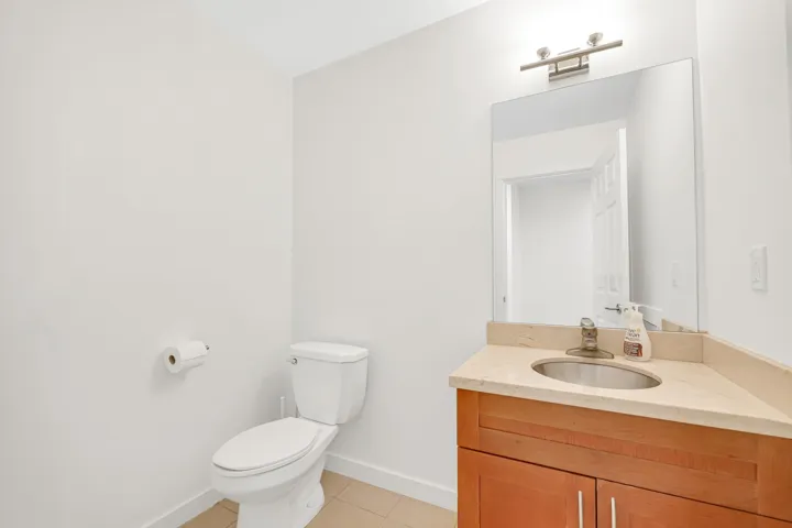 Half bath featuring toilet, tile patterned flooring, baseboards, and vanity