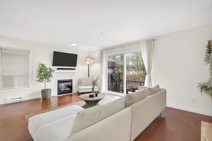 Living area featuring a fireplace with flush hearth, a baseboard radiator, hardwood / wood-style flooring, and baseboards