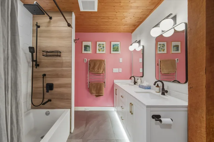 Bathroom featuring shower / tub combo with curtain, wood ceiling, double vanity, and a skylight