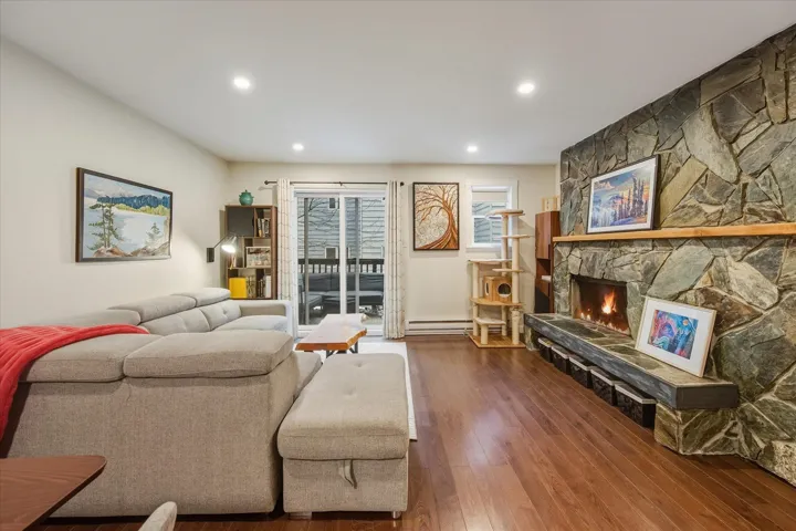 Living area with hardwood / wood-style flooring, a fireplace, a baseboard radiator, and recessed lighting