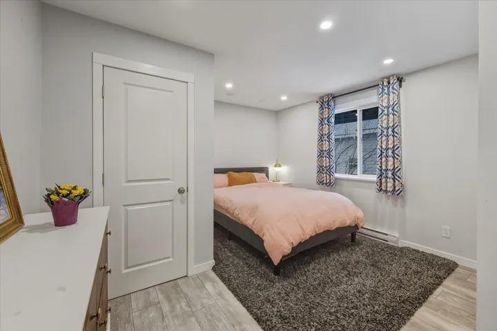 Bedroom featuring wood tiled floors, recessed lighting, and a baseboard heating unit