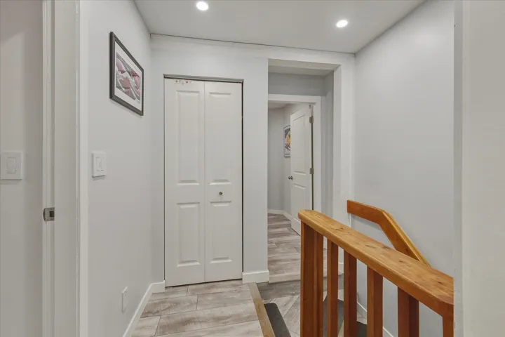 Corridor with light wood-style floors, recessed lighting, and an upstairs landing