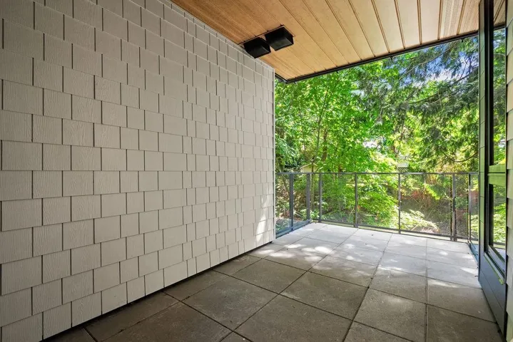 Outdoor patio with large format pavers, glass and metal railing, and a wood-paneled ceiling