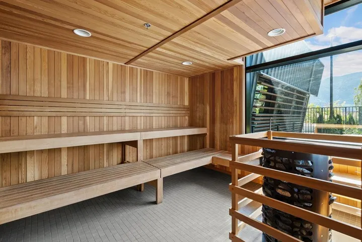 Custom sauna featuring wood paneling, built-in benches, recessed lighting, and a floor-to-ceiling window overlooking mountainous terrain