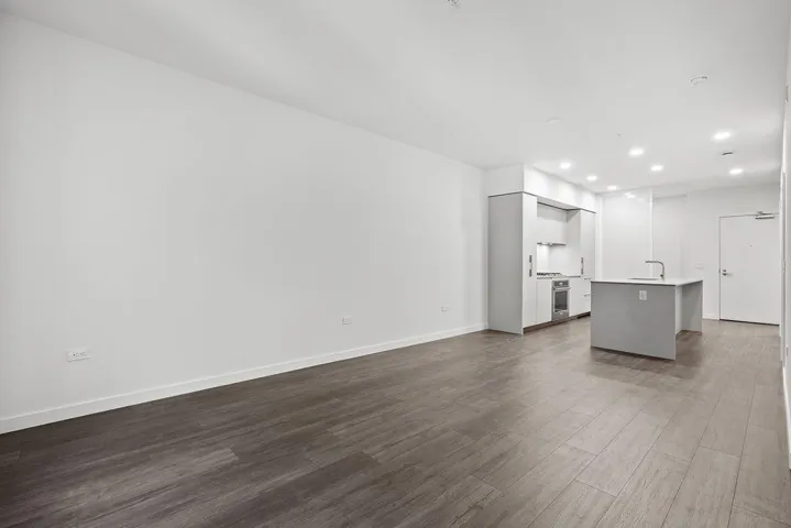 Open-concept living space featuring wood-finish flooring, recessed lighting, and a modern kitchen