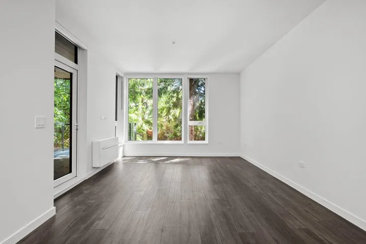 Spacious interior featuring dark wood-finish flooring, white walls, and abundant natural light from multiple large windows