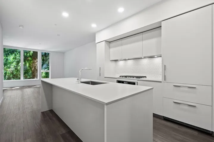 Modern kitchen featuring an expansive island with an undermount sink and a gooseneck faucet