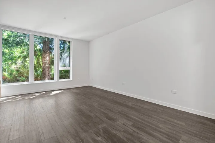 Expansive window wall with multiple panes, featuring white trim and a green outdoor backdrop