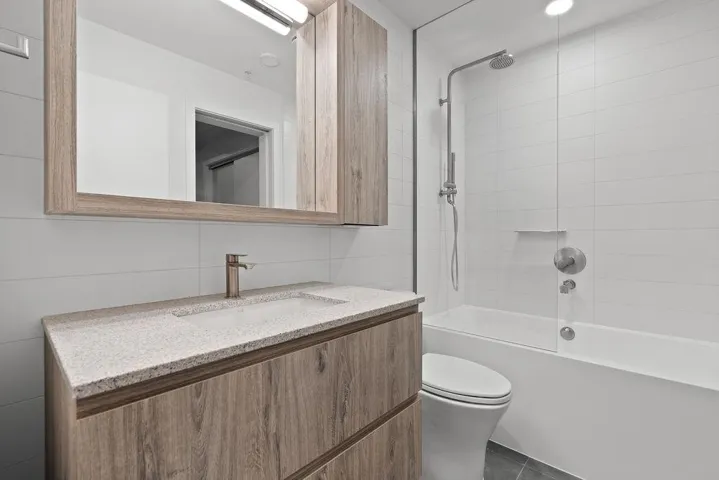 Bathroom featuring a wood-finish vanity with an integrated basin and speckled countertop