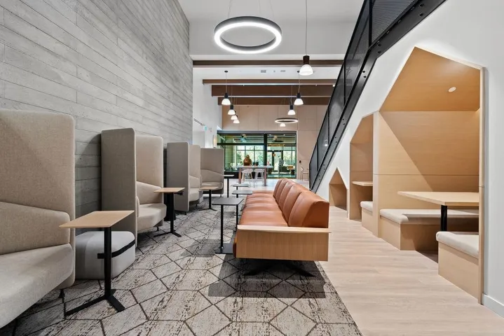 Open-concept common area featuring a concrete-paneled accent wall, patterned carpet, and wood-finish flooring