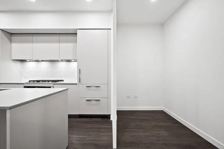 Modern kitchen featuring light gray cabinetry, integrated appliances, and a hexagon tile backsplash