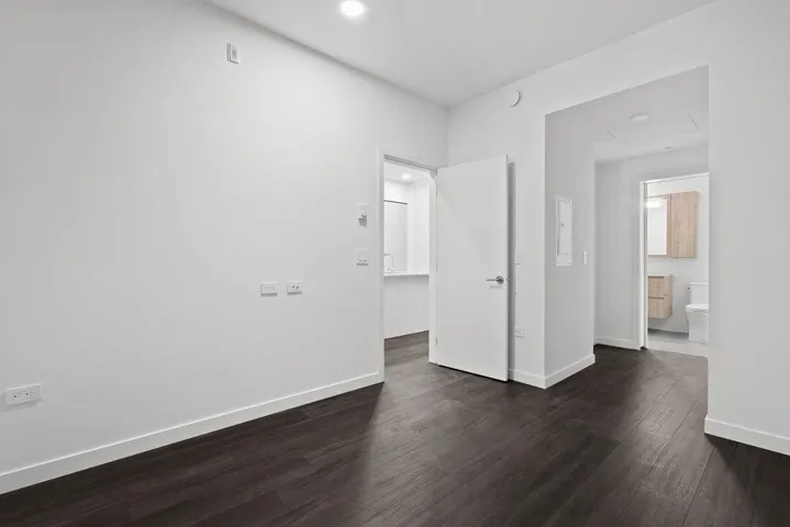 Spacious interior featuring dark wood-finish flooring, white walls, and recessed lighting