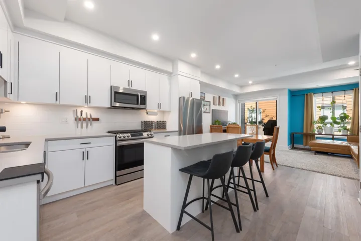 Kitchen featuring appliances with stainless steel finishes, a kitchen breakfast bar, backsplash, a center island, and white cabinets