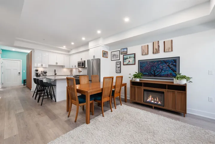 Dining area with recessed lighting, light wood-style floors, and a glass covered fireplace