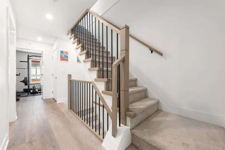 Staircase with wood finished floors and recessed lighting