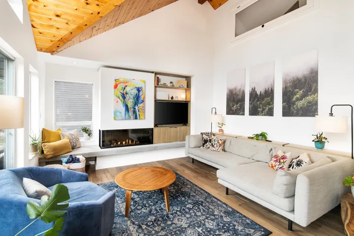 Living area with wood finished floors, high vaulted ceiling, and a glass covered fireplace