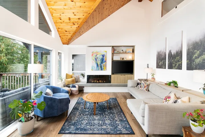 Living area with high vaulted ceiling, wood finished floors, a glass covered fireplace, wooden ceiling, and built in shelves