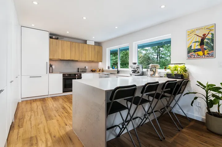 Kitchen featuring brown cabinets, a peninsula, a breakfast bar area, recessed lighting, and light stone counters