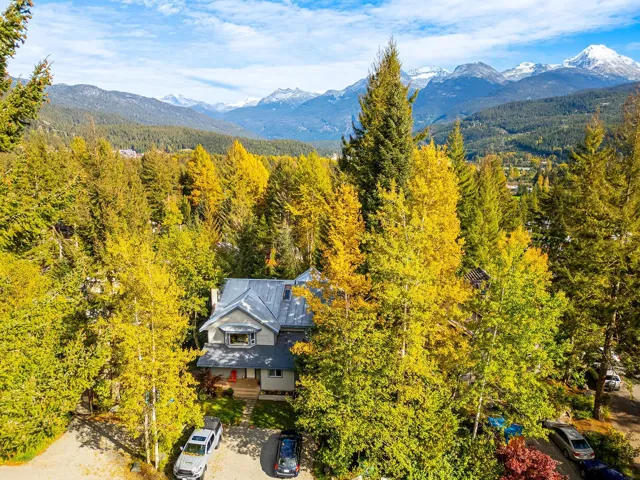 View of subject property featuring a mountain backdrop and a forest