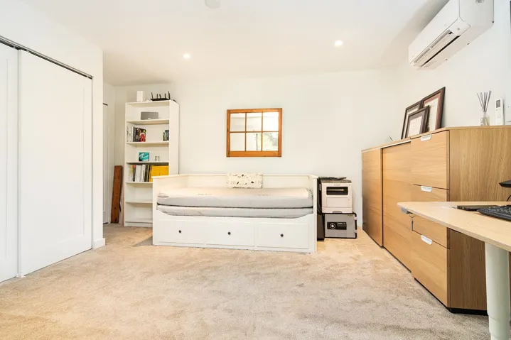 Bedroom with light carpet, a wall mounted air conditioner, recessed lighting, and a closet