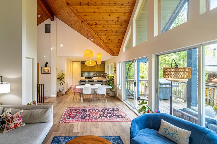 Living area with high vaulted ceiling, healthy amount of natural light, light wood-style floors, and a wood ceiling with exposed beams