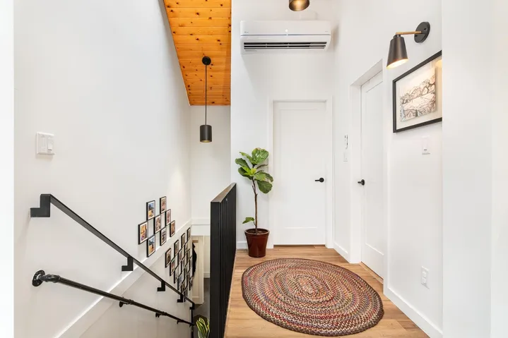 Corridor with wood finished floors, a wall mounted AC, and an upstairs landing