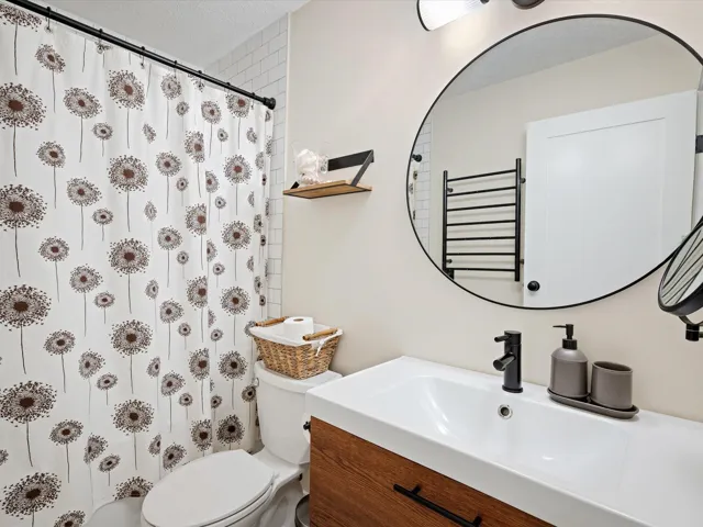 Bathroom featuring toilet, vanity, and a shower with shower curtain