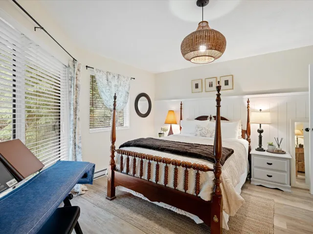 Bedroom featuring light wood-style flooring, a wainscoted wall, and a baseboard radiator