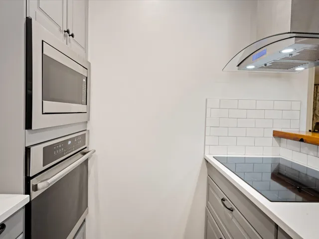 Kitchen with appliances with stainless steel finishes, tasteful backsplash, light countertops, and exhaust hood